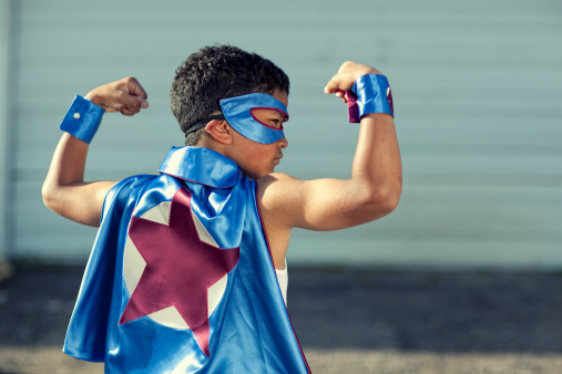 Portrait of a young African American superhero flexing his muscles. Vanquishing evil in a single afternoon. It is never too early to be super. 