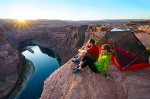 A couple camps on a ledge high above the Colorado and watches the sunset. Sunstar is real.