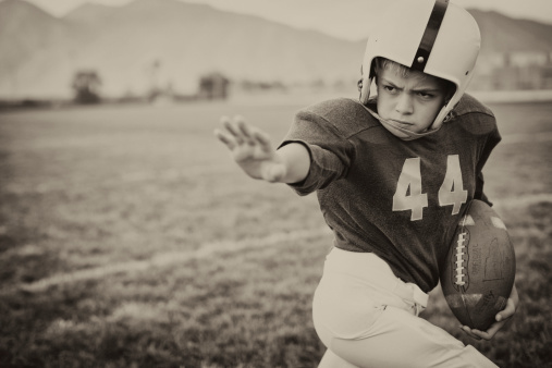 A young American Football boy applies the straight arm. It is football time. Vintage theme.