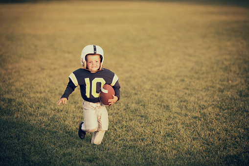 A young American boy practices tackle football in his backyard.