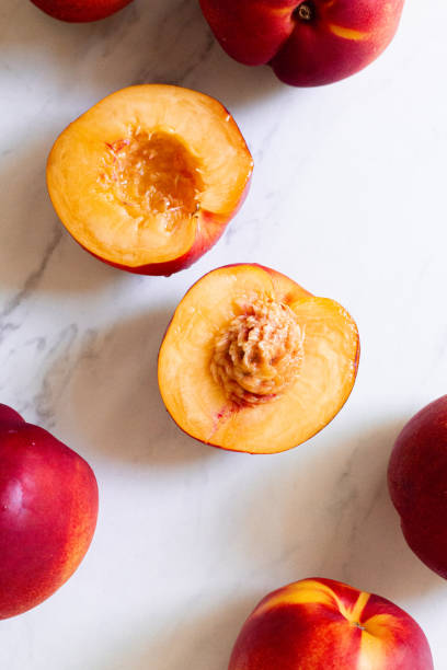 A fresh and juicy nectarine cut in half on white tile in the sun