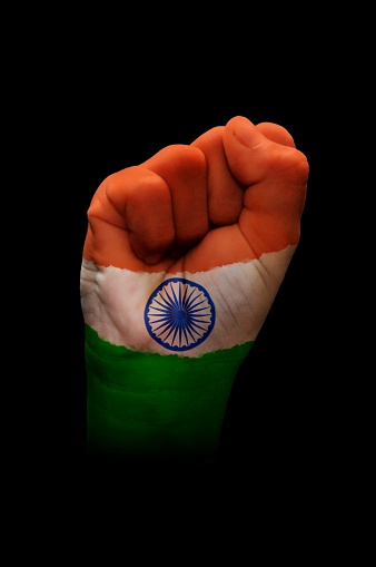 Vertical cutout of a fist of hand painted in three vibrant colored bands in orange, white and green with blue wheel with spokes or Ashok Chakra in the middle over black background. The image denotes confidence, strength and determination.There is no text and Copy space for text. Can be used for national festivals, events, national teams related backdrops like Indian Republic Day, Independence Day celebrations.