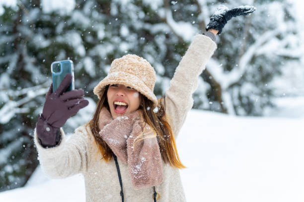 istock Asian woman using mobile phone taking selfie or vlogging during travel forest mountain covered in snow. 1586459918