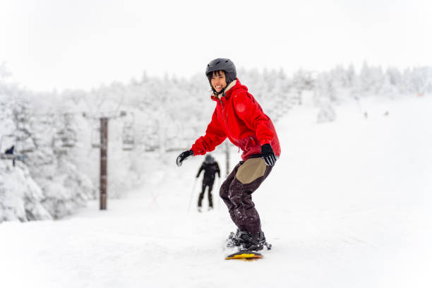 Asian woman practice snowboarding at ski slope Young Asian woman practice downhill sliding snowboard on snow mountain at ski resort. Attractive girl enjoy outdoor active lifestyle travel nature and winter extreme sport training on holiday vacation japanese snowboarder stock pictures, royalty-free photos & images
