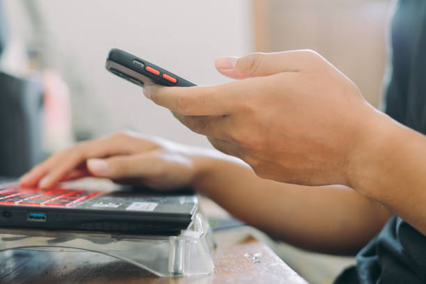 istock Hands of Asian man holding checking smartphone while typing on laptop keyboard 1586494309