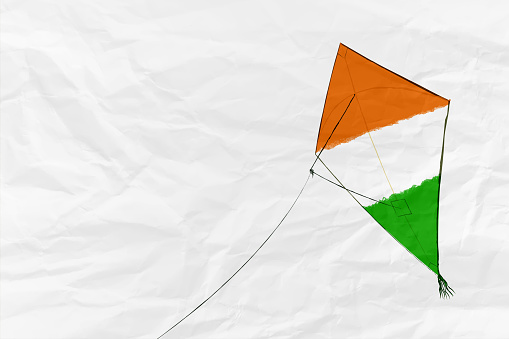 A horizontal plain blank empty white crumpled paper background with a kite flying with tricolored bands in saffron, white and green. A calm peaceful patriotic theme art. There is no people, no text and Copy space for text. These colors are in the flag of India, Niger and also of Ireland and Côte d'Ivoire (Ivory Coast) country. Can be used for national festivals, events, national teams related backdrops of these countries like Republic Day, Independence Day celebrations.