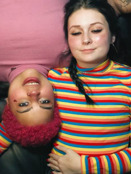 istock Two diverse young women lying on a couch together indoors. 1586500566