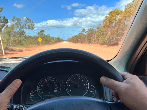 POV (point of view of a person) driver holding steering wheel while driving an off road car land vehicle on a long off road in Cape York peninsula in tropical far north of Queensland, Australia.