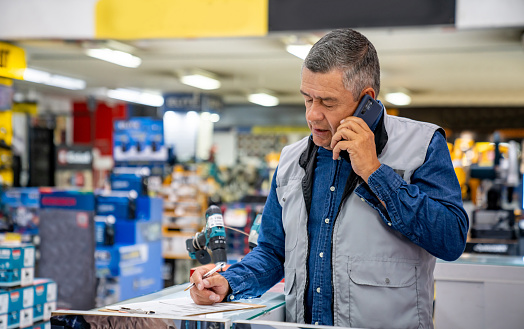 Latin American business owner working at a hardware store and talking on the phone