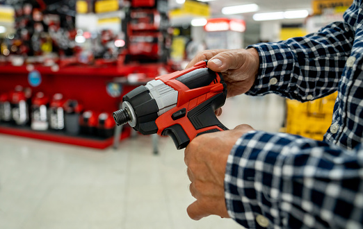 Close-up on a man buying a drill at a hardware store - construction industry concepts