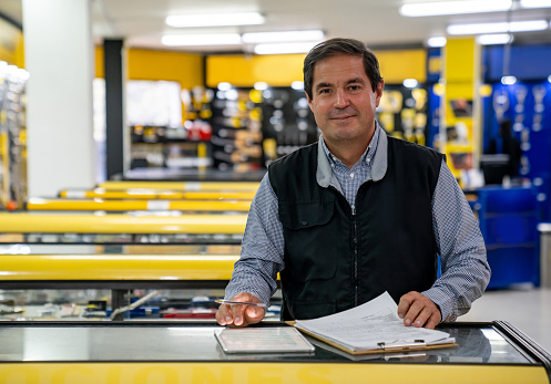 Portrait of a Latin American business owner working at a hardware store and looking at the camera smiling