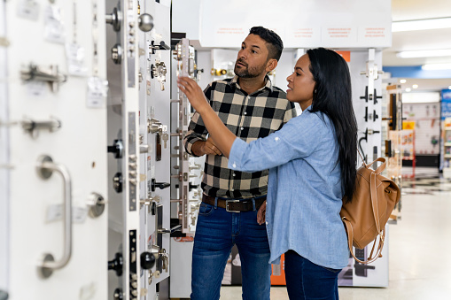 Latin American couple looking at security locks for their house at a hardware store