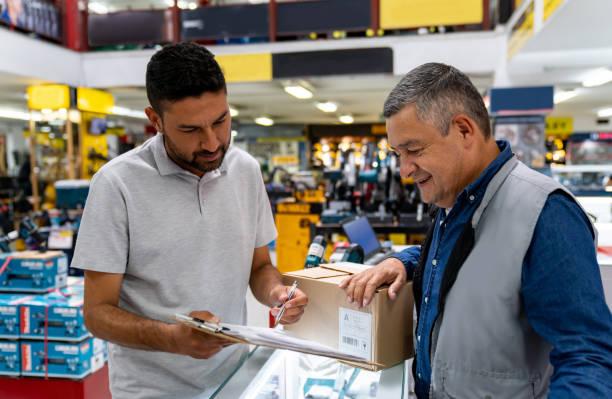 istock Man delivering a package at a hardware store and asking for a signature 1586524533