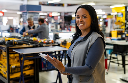 Happy Latin American saleswoman working at a hardware store and looking at the camera smiling