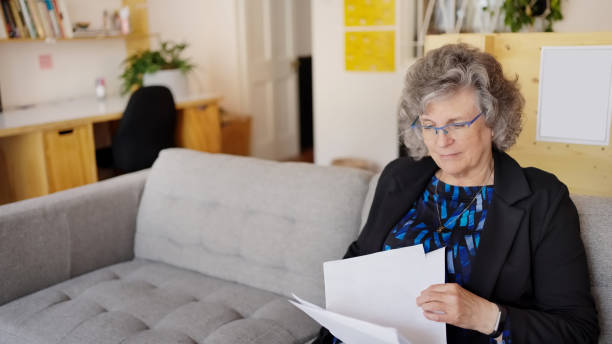 istock Senior businesswoman going through documents sitting on sofa in office 1586580148