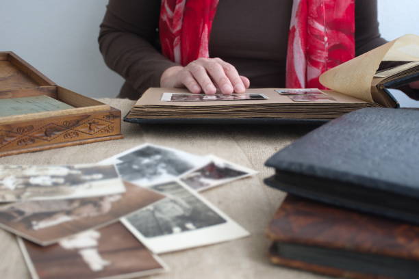 Midsection of woman holding old photo album Midsection of woman holding old retro photo album with vintage monochrome photographs in sepia color genealogy stock pictures, royalty-free photos & images