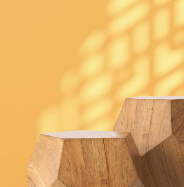 istock Two modern geometric shape brown wooden podium table, pentagon side in sunlight, Chinese window grill shadow on blank yellow wall 1586586715