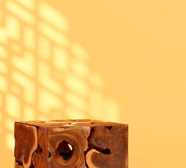 istock Brown natural log wood cube podium table in sunlight, Chinese round window grill shadow on blank vibrant yellow wall 1586590428