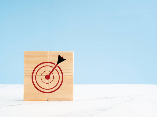 istock Darts target icon on wooden cubes on the marble floor with a light blue background 1586654349