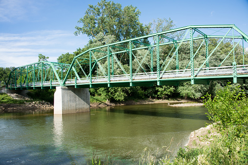 Truss bridge over the Wabash River in Indiana with blue sky and green trees