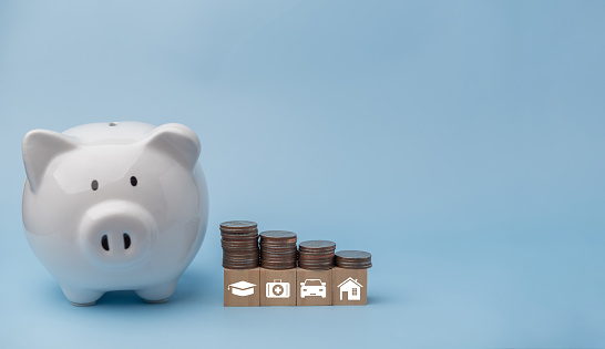 piggy bank and coins stacking with icon saving energy and money on cube wood . business finance and banking investment, tax, insurance home and car concept.