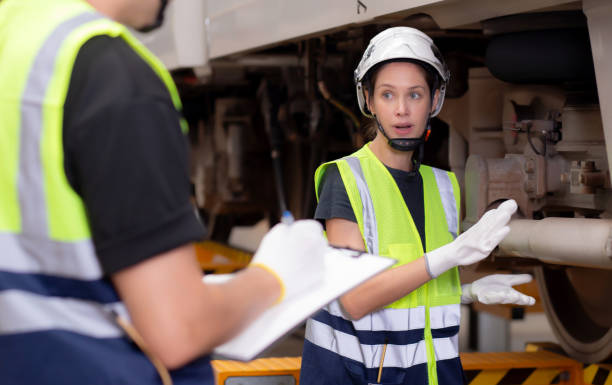 istock Young caucasian engineer man and woman or worker checking electric train for planning maintenance looking document on clipboard in station, transport and infrastructure, inspector check transport. 1586656754