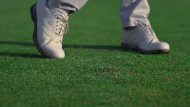Golfer feet hitting ball on fairway course. Golf man swinging shot on training.