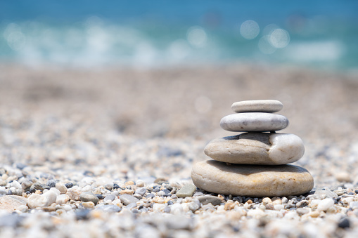 Beach shoot themes: Panoramic view of pebbles stack in a tropical beach with the sun at midday.