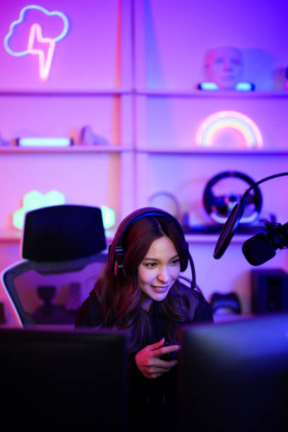 istock Asian e-sport girl live streaming broadcast game tournament online in her channel while using joystick for playing with friend team in entertainment neon room 1586683241