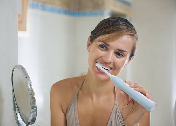istock Young woman brushing teeth with electric toothbrush 158670174