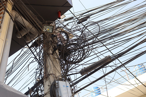 Messy electrical cables in Nepal example of uncovered optical fiber technology, Light pole with tangled wires, line on electric pole on street