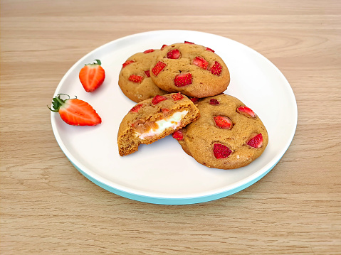 Homemade of strawberry soft cookies served on a white plate and placed on the wooden table, ready to eat, snack time
