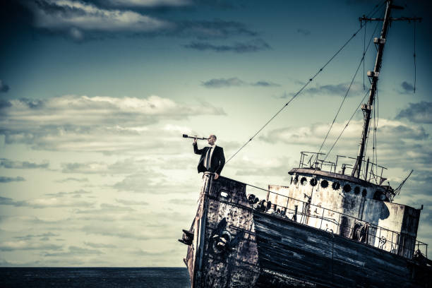 Overcome the economic crisis Businessman looking through spyglass from sinking shipwreck. fishing boat sinking stock pictures, royalty-free photos & images