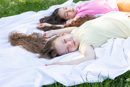Two Real Little Girls, Siblings Lay on Grass, Lawn In Summer Park. Joyful Children Spend Time in Nature, Meadow. Lifestyle, Carefree Childhood, Best Friends. Horizontal Plane High quality photo