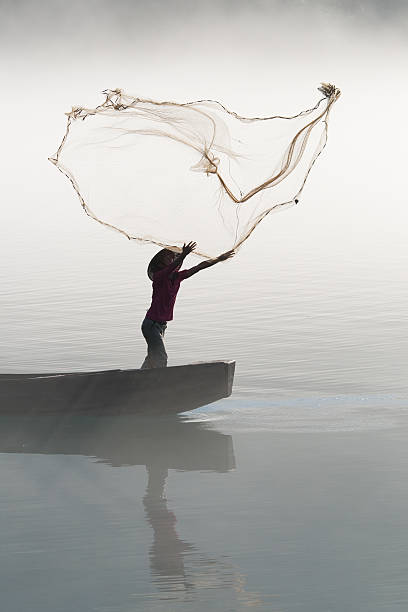 Fisherman casting net on river stock photo