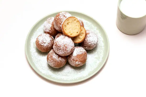 Photo of Flatly Fat Thursday Carnival or Tlusty Czwartek, Christian tradition. Zeppole Or Paczki On Plate With Powdered Sugar, Cup Of Milk On Table. Doughnut, Delicious Donuts. Horizontal Plane