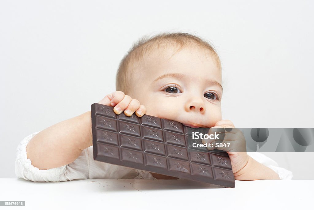 Baby, Chocolate baby eating chocolate, looking at camera 6-11 Months Stock Photo