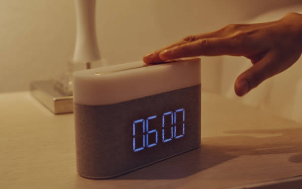 la main des jeunes femmes éteint le réveil numérique sur la table de chevet dans la chambre à coucher à la maison. - turn signal photos et images de collection