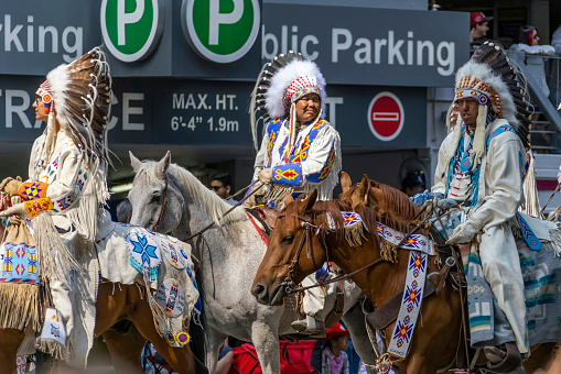 Calgary, Alberta, Canada. July 7, 2023. Some First Nations people wearing traditional cloths while riding horses at a public festival parade.