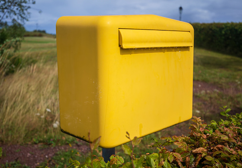 Gele Duitse postbox één in de groene weide in dorp