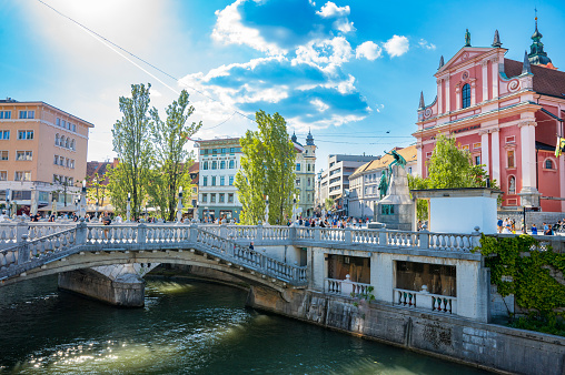 Ljubljana city view with the Tromostovje three bridges over the Ljubljanica river running through the capitol city of Slovenia during a beautiful springtime day.