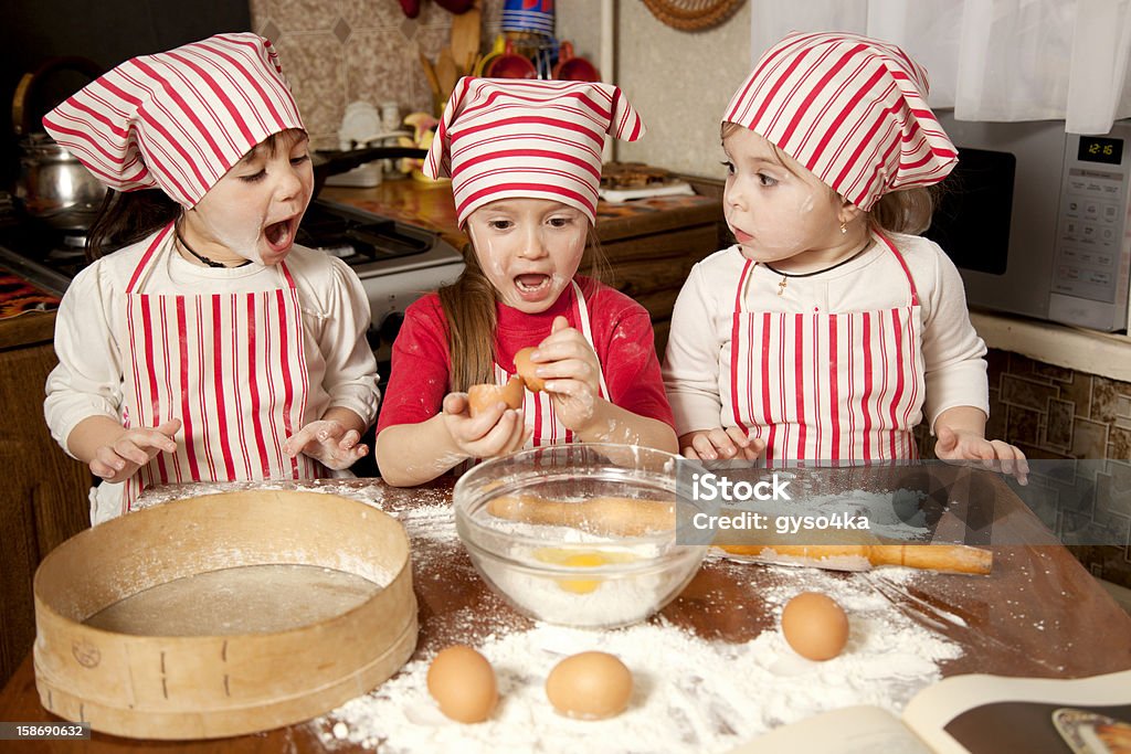 Three little chefs enjoying in the kitchen Three little chefs enjoying in the kitchen making big mess. Little girls making bread in the kitchen 4-5 Years Stock Photo