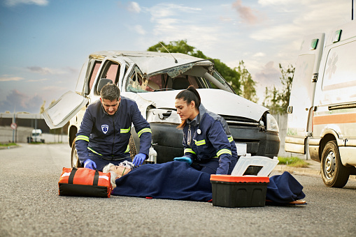 Paramedics providing first aid to man injured in car accident.