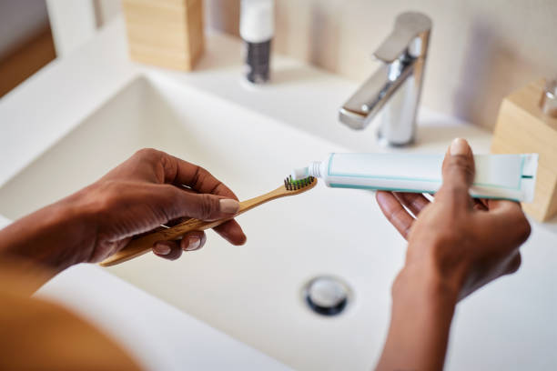 African woman put tooth paste on ecological toothbrush stock photo