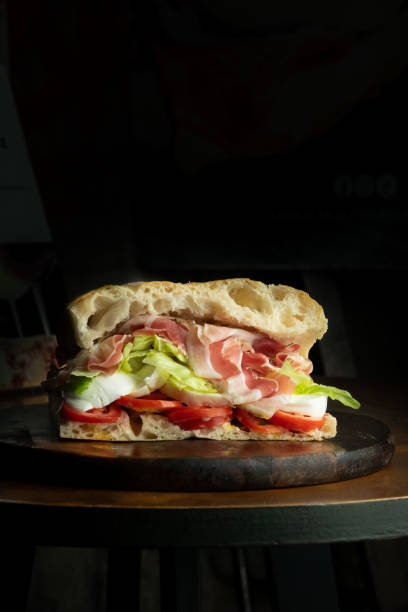 Sandwich with cooked ham tomato mozzarella and basil