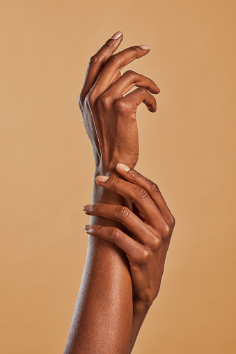 African american woman hands applying moisturizing cream. Black woman beauty gesturing with hands isolated on brown background. Female elegant hands touch each other with a movement of lightness.