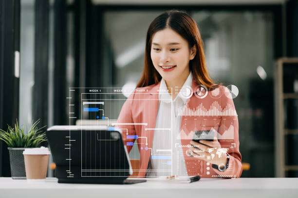 istock Asian Businesswoman hand Project manager working and update tasks and Gantt chart scheduling virtual diagram.with smart phone, tablet and laptop in office. 1586925996