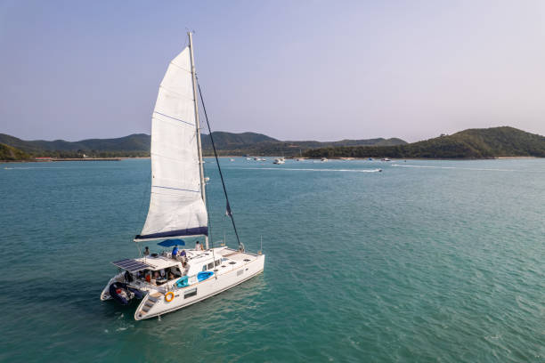 vue aérienne d’un yacht à moteur privé de luxe sur l’océan pendant l’été. de jolis jeunes hommes et femmes qui traînent, célébrant des vacances de vacances tout en naviguant en catamaran au coucher du soleil d’été. - travel locations sea mediterranean sea wind photos et images de collection