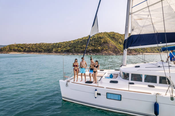 vue aérienne d’un yacht à moteur privé de luxe sur l’océan pendant l’été. de jolis jeunes hommes et femmes qui traînent, célébrant des vacances de vacances tout en naviguant en catamaran au coucher du soleil d’été. - travel locations sea mediterranean sea wind photos et images de collection