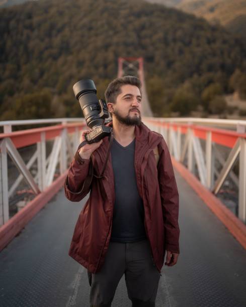 istock Professional photographer taking photos with his digital camera on a bridge 1586999109